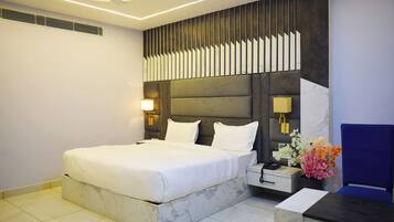 A modern hotel room with a large bed, a desk with a chair, and a decorative wall panel.
