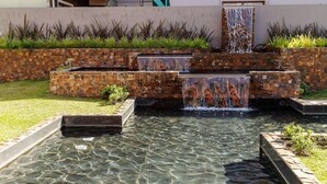 Un élément décoratif aquatique à plusieurs niveaux, avec un bassin d’eau claire à l’avant.