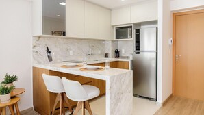 Une cuisine moderne dotée d’un plan de travail en marbre, d’appareils électroménagers en acier inoxydable et d’éléments décoratifs en bois.