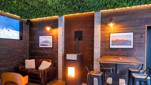 A cozy lounge area with a leather sofa, a table with chairs, a fireplace, and framed pictures on the walls. - Apart Hotel des Cols  (Borderes-Louron)