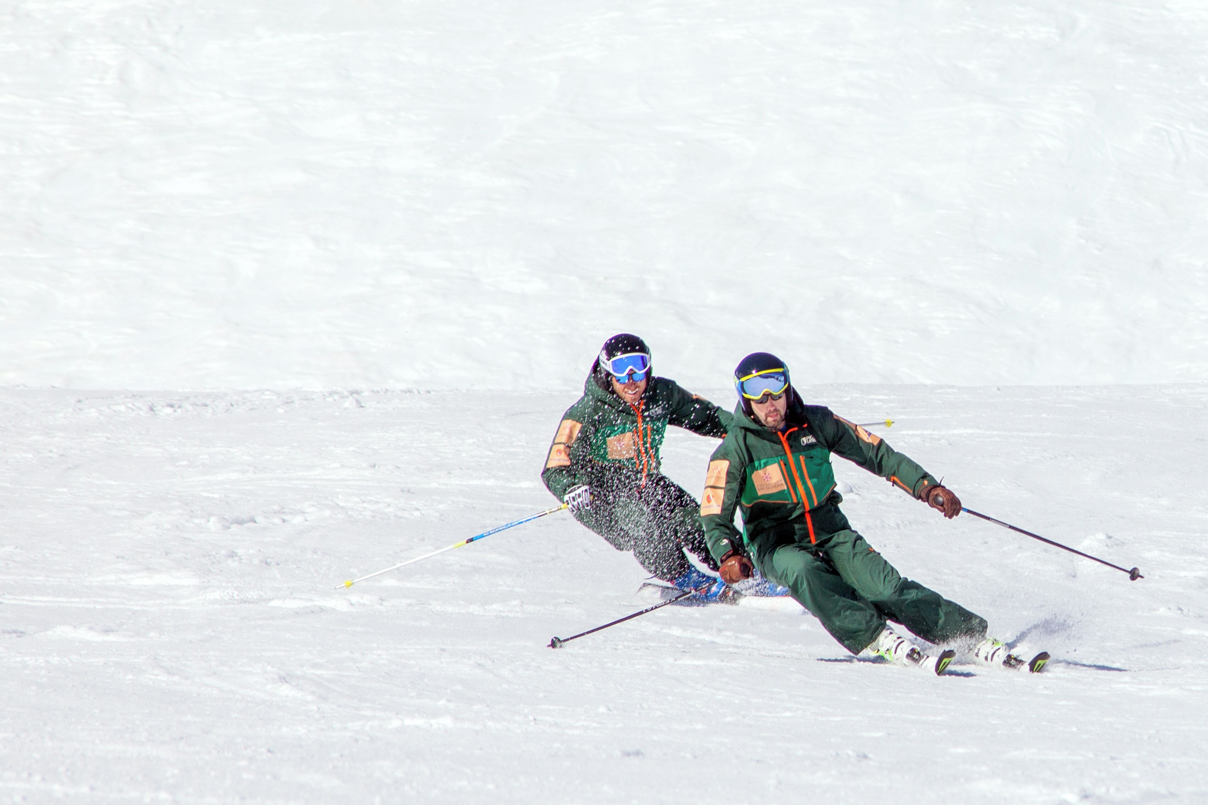 Deux personnes font du ski sur une pente enneigée.