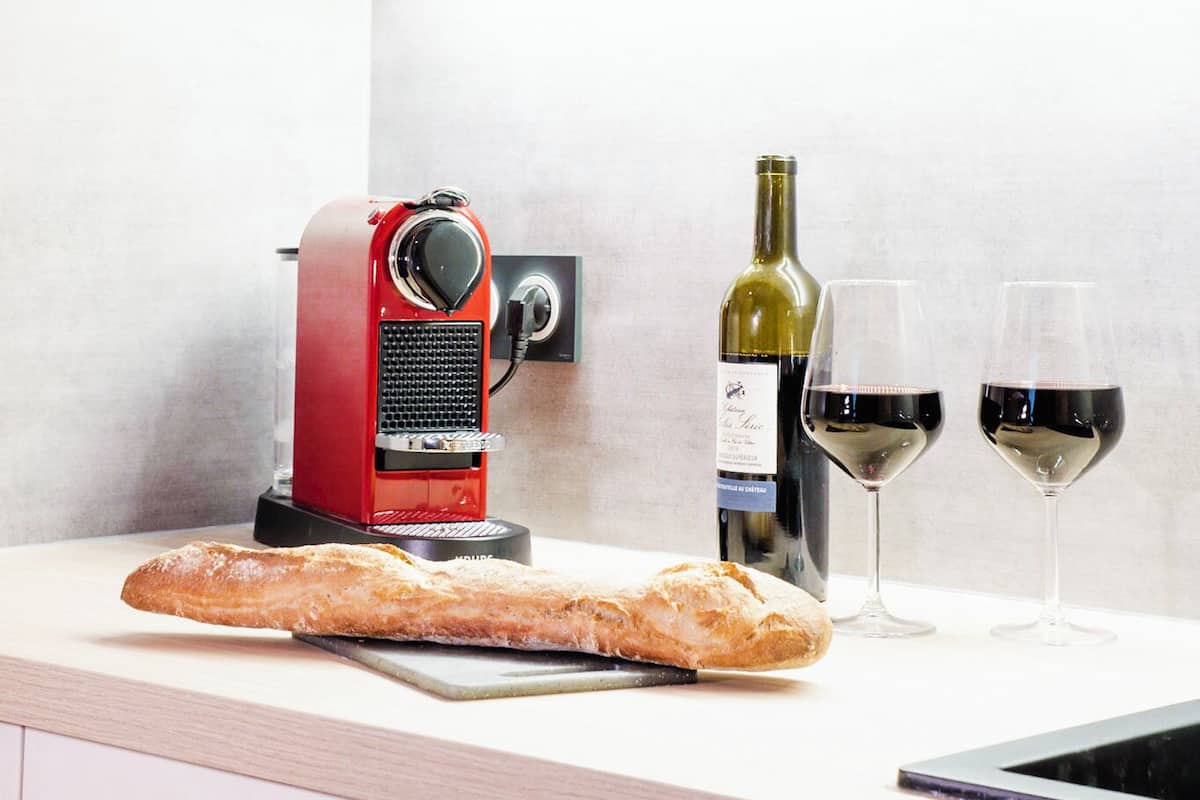 A kitchen with a bread slicer, wine bottle, and glasses on the counter.
