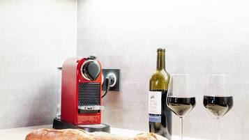 Una cocina con un corta pan, una botella de vino y vasos sobre la encimera.