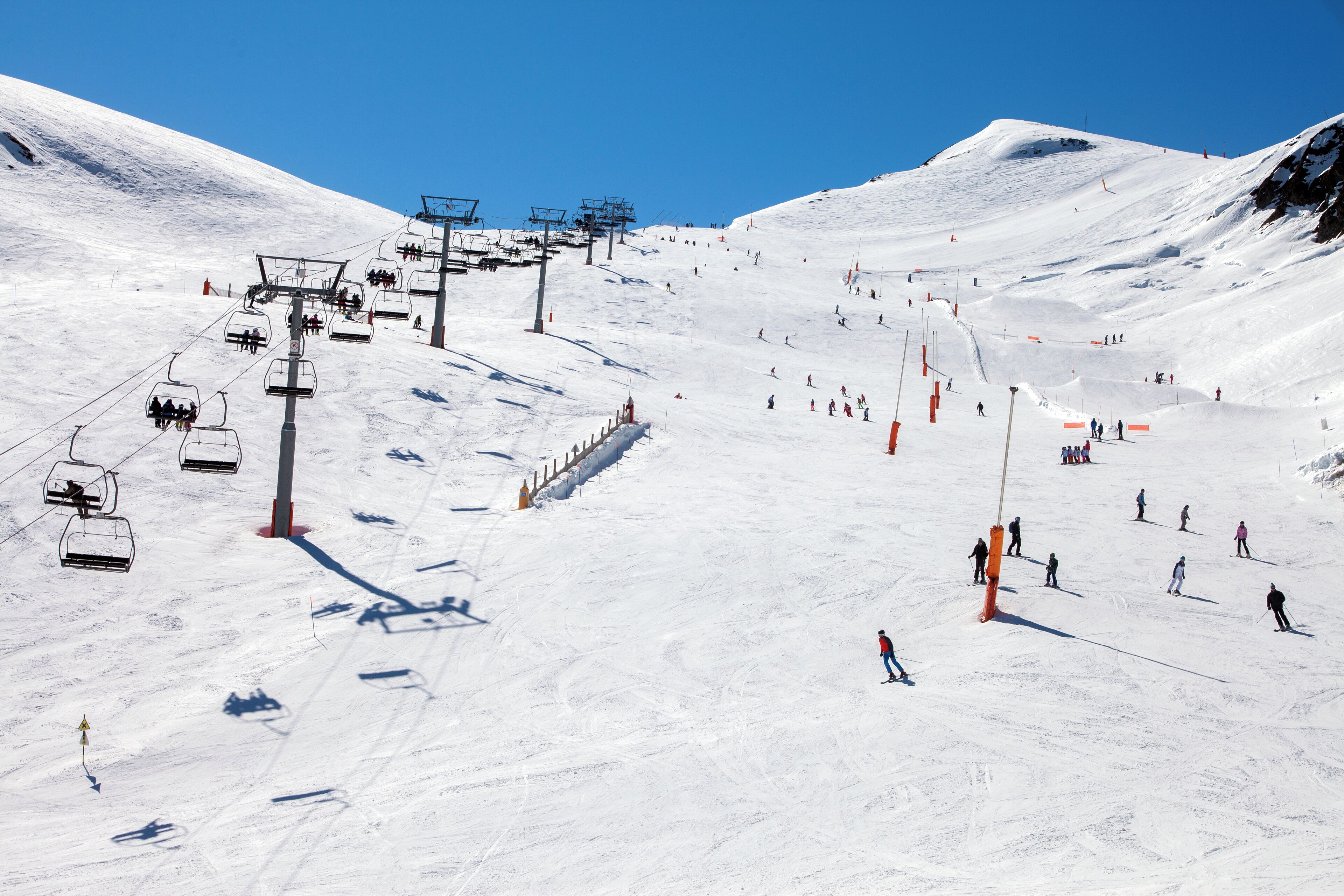 Une piste de ski avec un télésiège, des skieurs et un paysage enneigé.