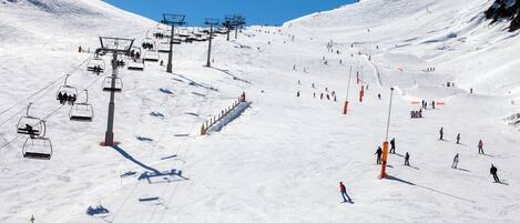 Une piste de ski avec un télésiège, des skieurs et un paysage enneigé.