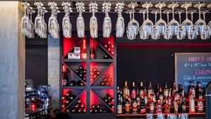 A bar area with a wine rack, shelves of bottles, and glasses. - Apart Hotel des Cols  (Borderes-Louron)