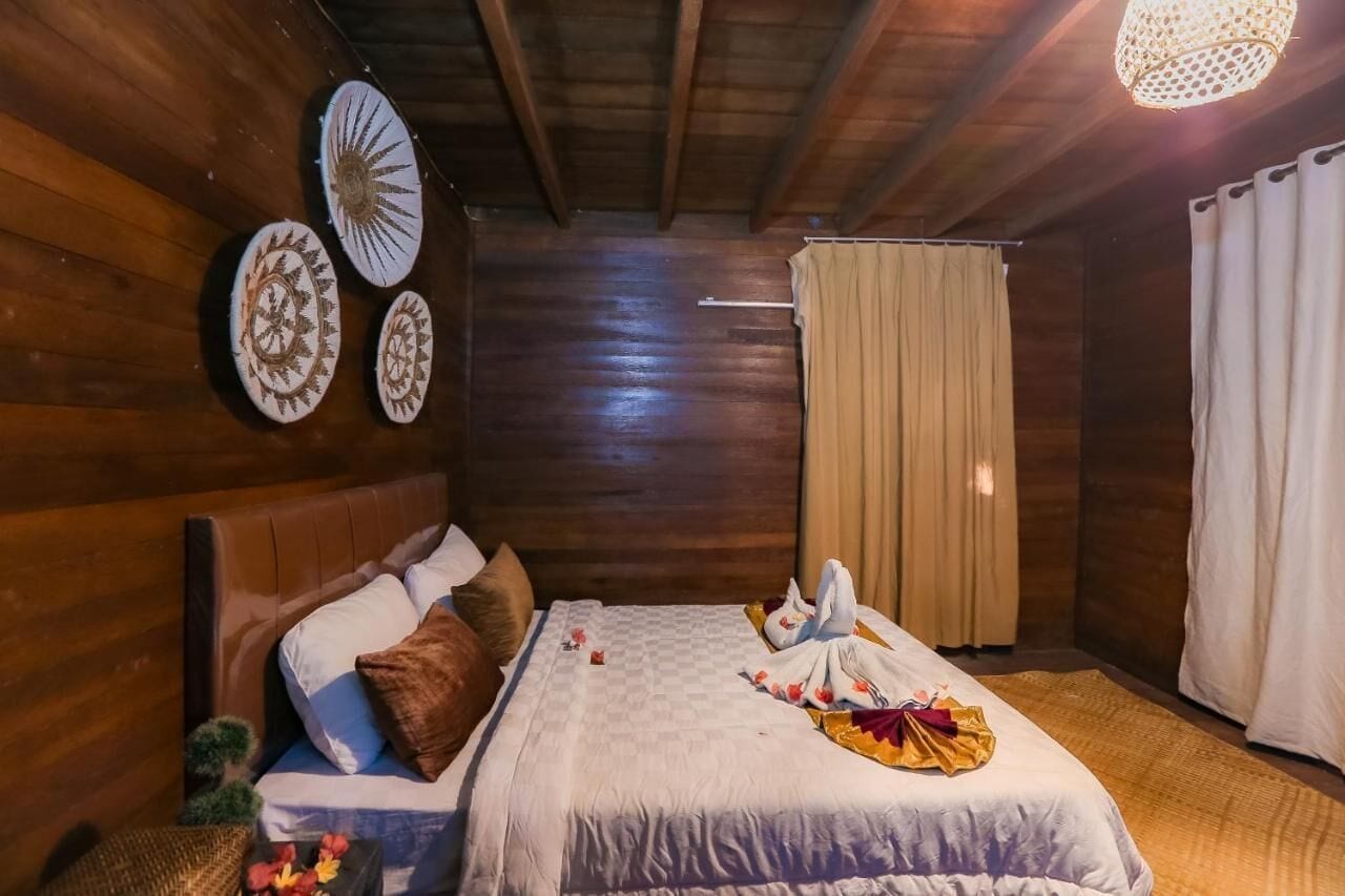 A wooden room with a bed, a headboard, and a ceiling fan.
