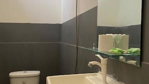 Een badkamer met een wit toilet, een witte wastafel en een spiegel.