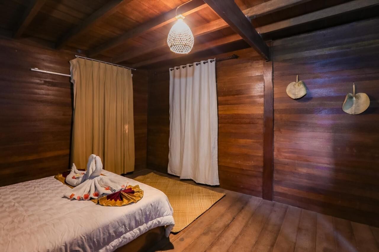 Um quarto com painéis de madeira, uma cama, um candeeiro pendente e dois objetos decorativos fixados na parede.