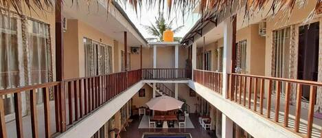 A multi-level building with a central pool, balconies, and outdoor seating areas.