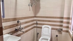 A small bathroom with a toilet, sink, and shower. - Hotel Wanderlusts Rigyal Lachung (Chungthang)