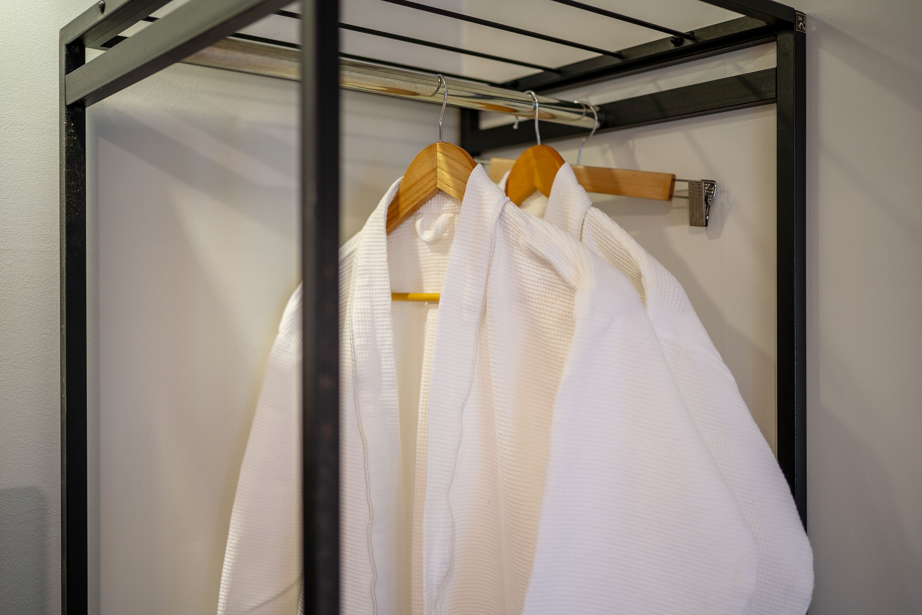 A metal rack with wooden hangers holding white robes.