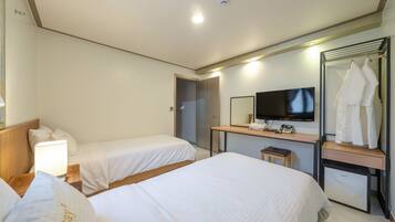 Habitación de hotel con dos camas, un escritorio con televisor y un espejo.