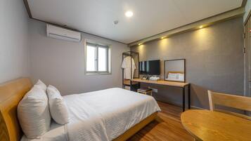 Un dormitorio con cama, escritorio, silla, televisor y ventana.