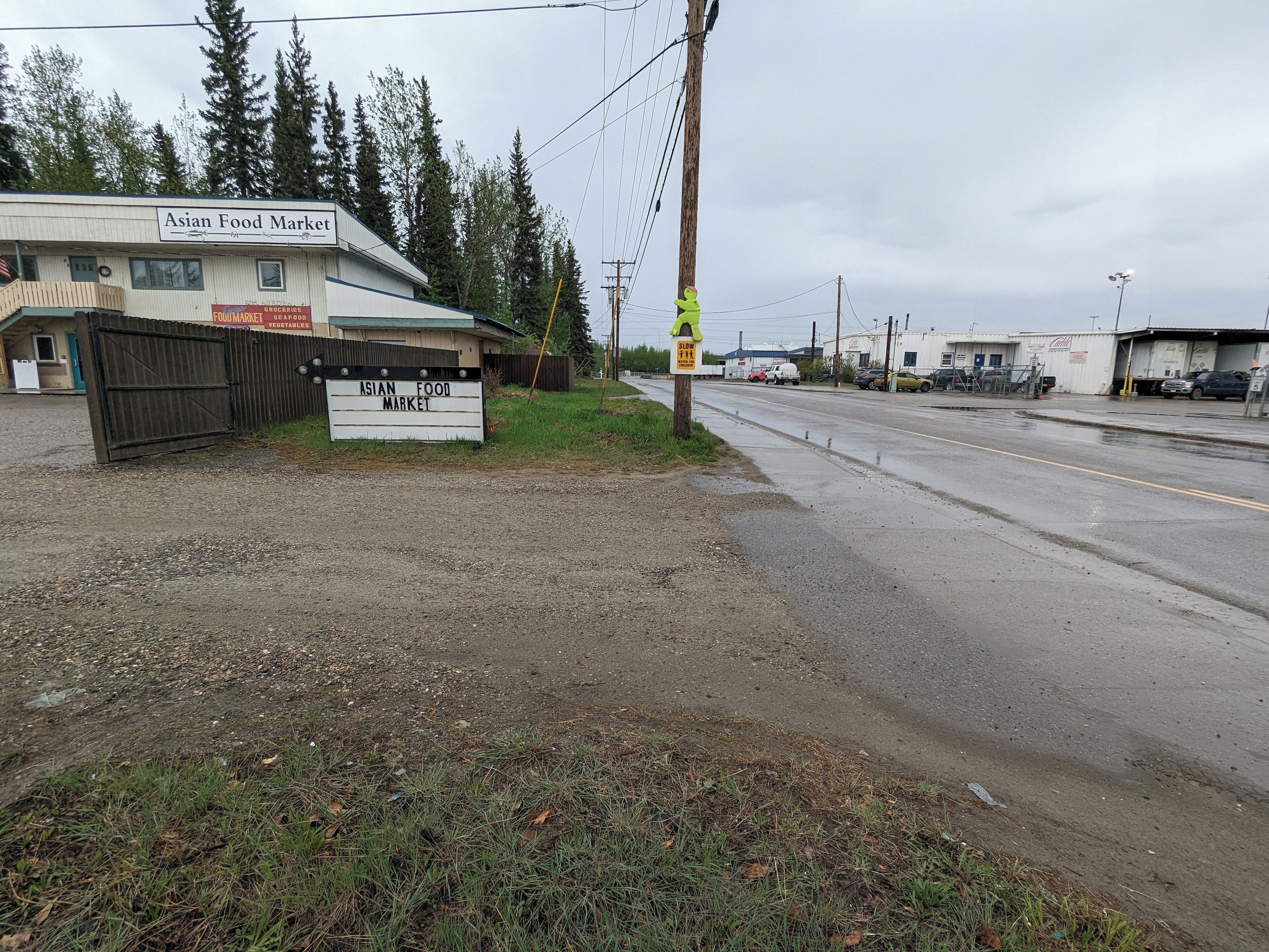 A gravel parking area in front of the Asian Food Market.