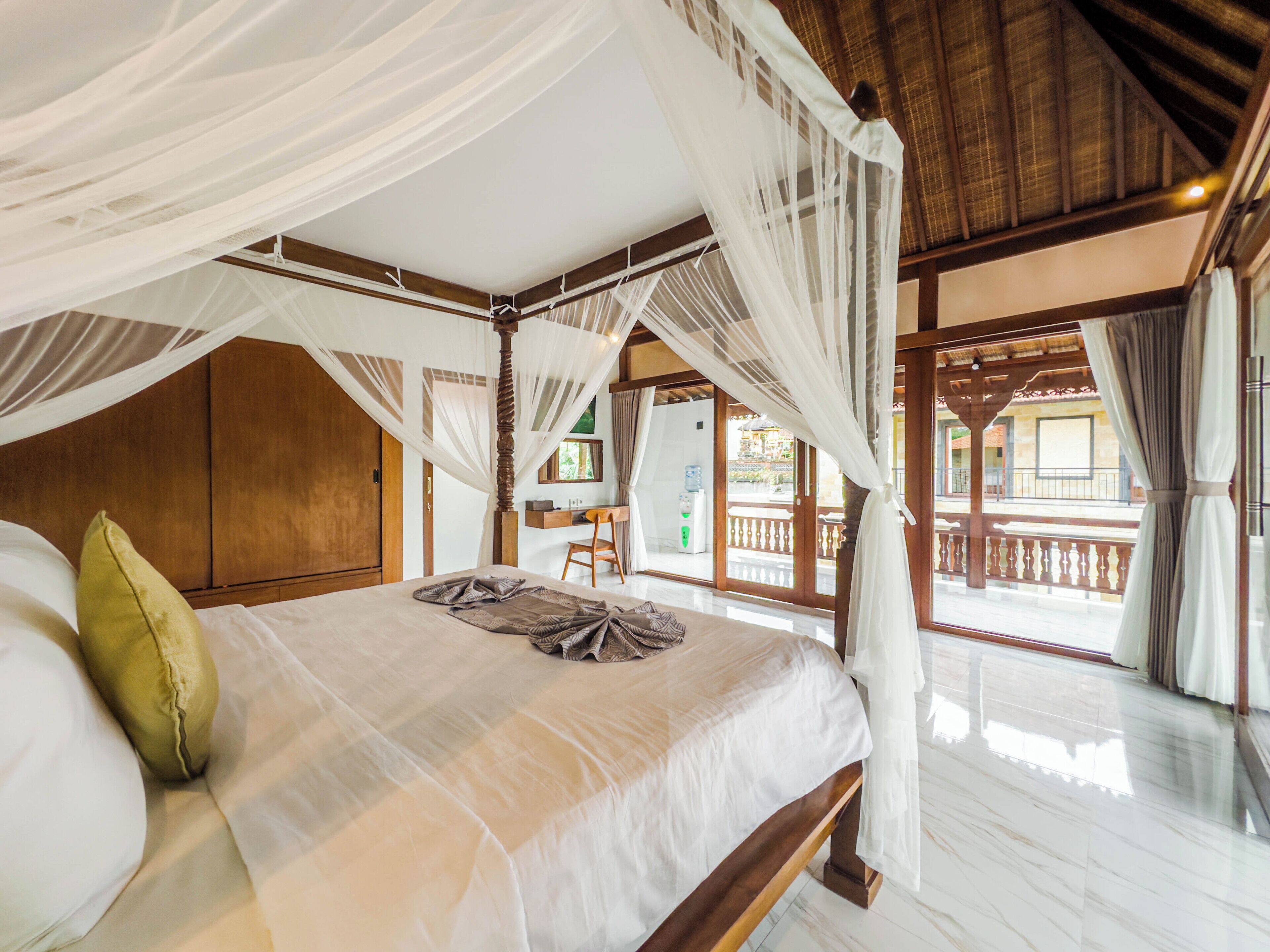 Une chambre spacieuse avec un grand lit, une tête de lit en bois et un baldaquin.
