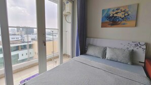 Un dormitorio con cama, un cuadro, una ventana y vistas a edificios.