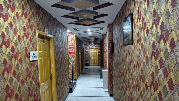 A hallway with patterned walls, a sign indicating room A-2 Queen, and a door labeled "Kitchen". - Al-Banaras Hotel  (Rawalpindi)