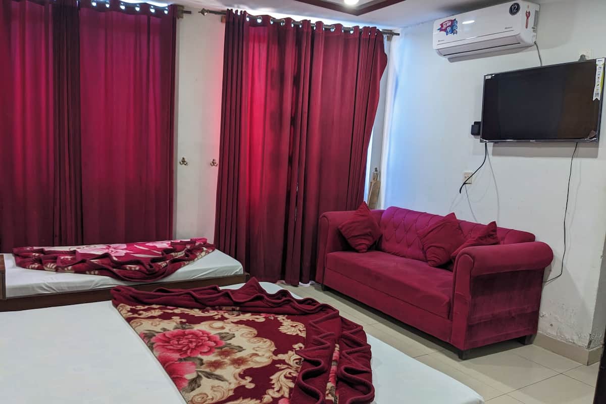Ein Zimmer mit einem Bett, einem roten Sofa und einem an der Wand befestigten Fernseher.