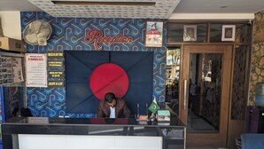 A reception desk with a large red circular design, a framed portrait above it, and a sign indicating 'Reception'. - Al-Banaras Hotel  (Rawalpindi)