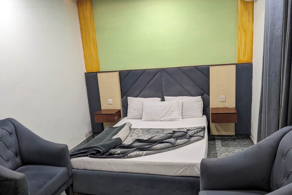 Ein Hotelzimmer mit einem Bett, zwei Nachttischen und zwei Sesseln.