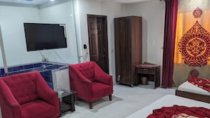 A hotel room with a bed, two red armchairs, a TV, a wardrobe, and a small table. - Al-Banaras Hotel  (Rawalpindi)