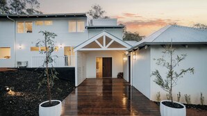A modern house with a covered walkway, two potted plants, and a well-lit entrance. - The Vintners: Where luxury meets nature, five master suites & spacious living (Peerabeelup)