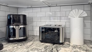 A kitchen with a coffee maker, toaster, and paper towel holder on a marble countertop.