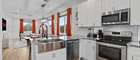 A modern kitchen with white cabinets, stainless steel appliances, and a central island.