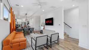 A modern living room with a sectional sofa, a coffee table, and a TV mounted on the wall.
