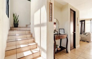 A staircase leading to a room with a welcome sign, a desk with a mirror, and a sofa.