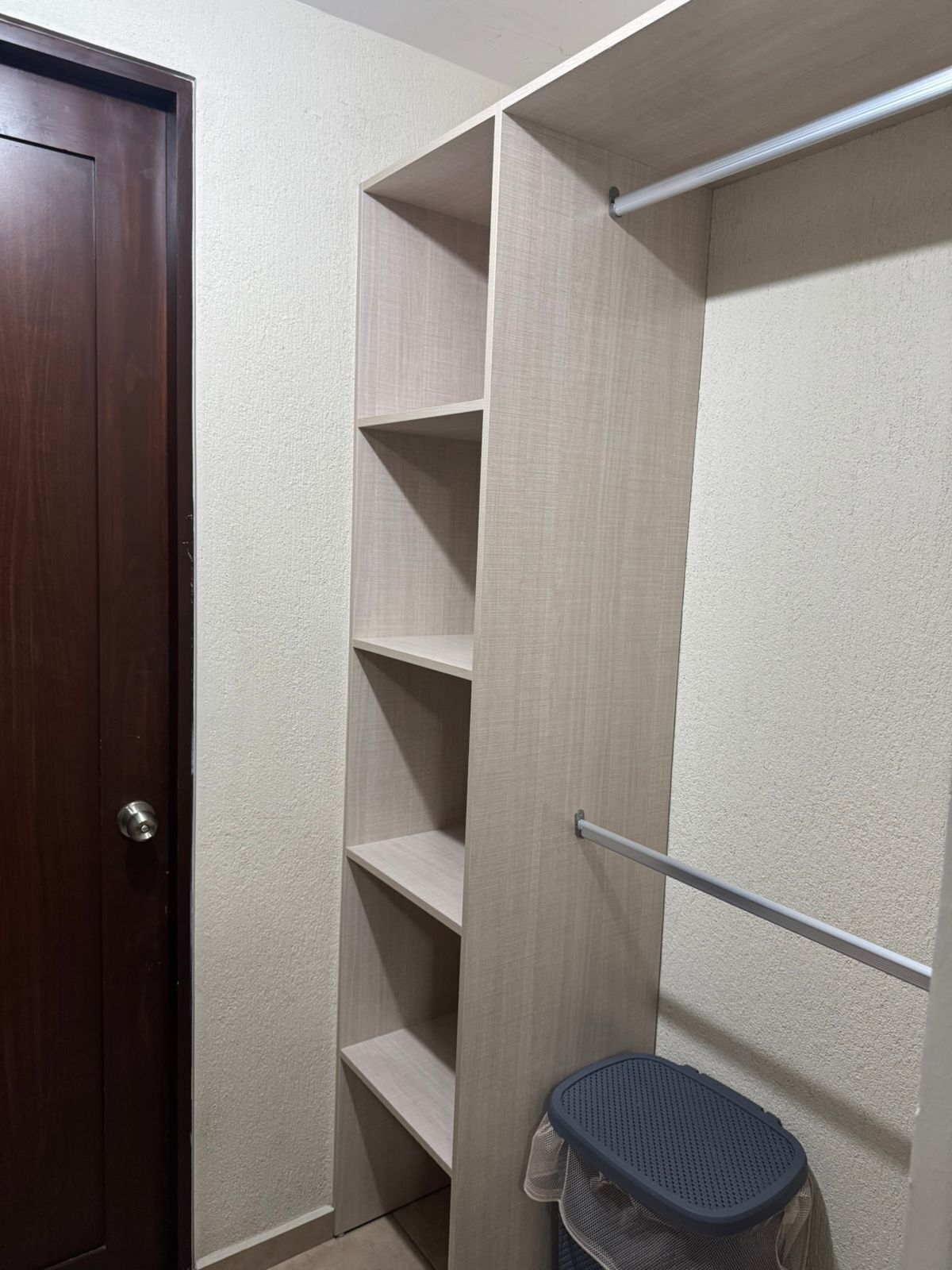 A walk-in closet with wooden shelves and a metal rod for hanging items.