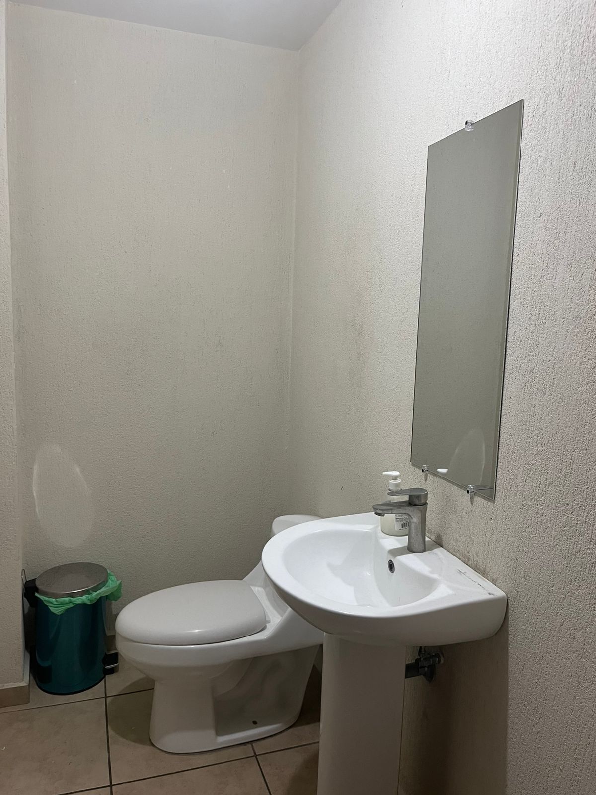 Une petite salle de bain avec des toilettes, un lavabo et un miroir au mur.