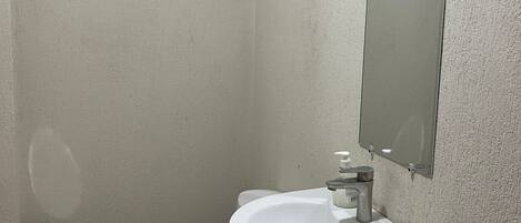 Une petite salle de bain avec des toilettes, un lavabo et un miroir au mur.