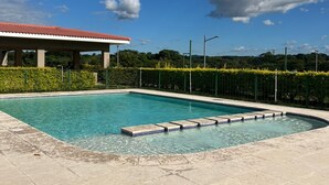 En rektangulär swimmingpool med kakelbeklädda trappsteg som leder ner i den, omgiven av en kakelbelagd poolterrass.