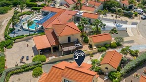 A residential area with houses featuring red-tiled roofs, a swimming pool, and a landscaped garden. - Spacious 3BR Villa Retreat for 6 Guests & 3.5 Baths at Mesa Vista 26 by Bocobay (Noord)