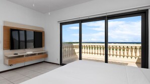A modern bedroom with a large bed, a TV, and a balcony with a view of the ocean. - Spacious 3BR Villa Retreat for 6 Guests & 3.5 Baths at Mesa Vista 26 by Bocobay (Noord)
