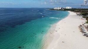 A beach with clear turquoise waters, white sand, and a few buildings in the background. - Spacious 3BR Villa Retreat for 6 Guests & 3.5 Baths at Mesa Vista 26 by Bocobay (Noord)