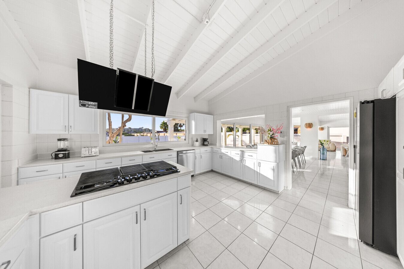 A modern kitchen with white cabinetry, a built-in stove, and a large window overlooking a balcony.