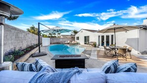 Un patio trasero con piscina, mobiliario exterior y una zona de terraza.