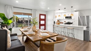 Una cocina moderna con armarios blancos, electrodomésticos de acero inoxidable e iluminación colgante.