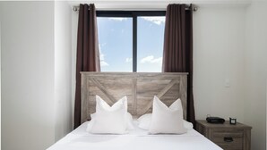 A bed with a wooden headboard, two white pillows, and a nightstand with a radio and a small container. - Serenity in the Heart of Santo Domingo 80m2 Apartment Retreat (Santo Domingo)