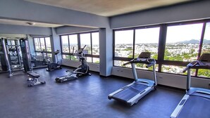 A spacious gym with multiple treadmills, stationary bikes, and weight machines. Large windows offer a view of the cityscape. - Serenity in the Heart of Santo Domingo 80m2 Apartment Retreat (Santo Domingo)