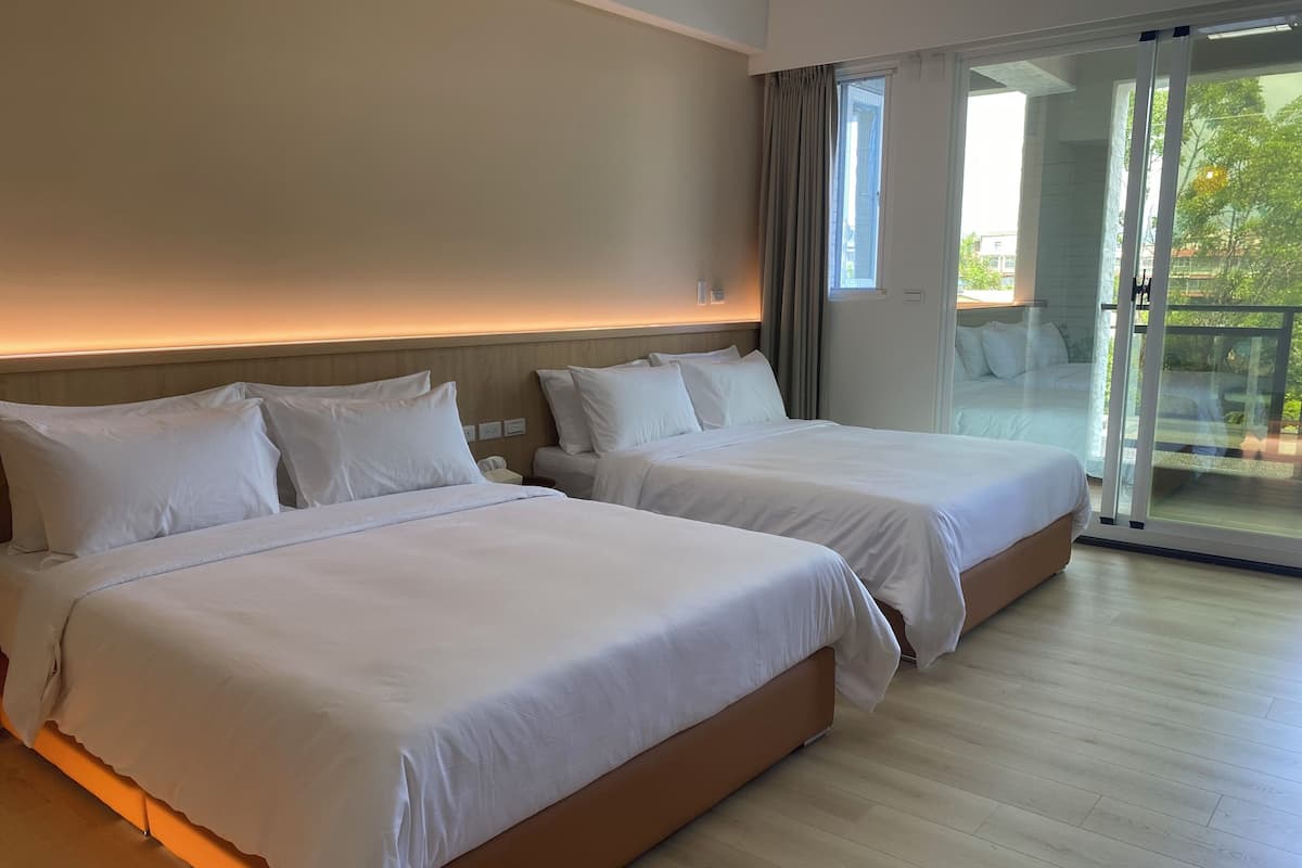 A hotel room with two beds, a large sliding glass door to a balcony, and a modern design.