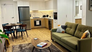 A modern living room with a green sofa, a coffee table, and a dining area with chairs and a table.