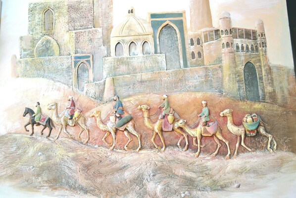 A mural of camels and riders on a desert landscape with a castle in the background.
