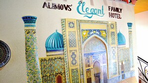 A wall mural of a traditional building with geometric patterns and blue domes. - Elegant Hotel (Tashkent)