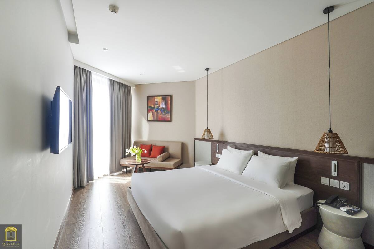Une chambre d’hôtel avec un grand lit, un canapé, une petite table et un tableau au mur.