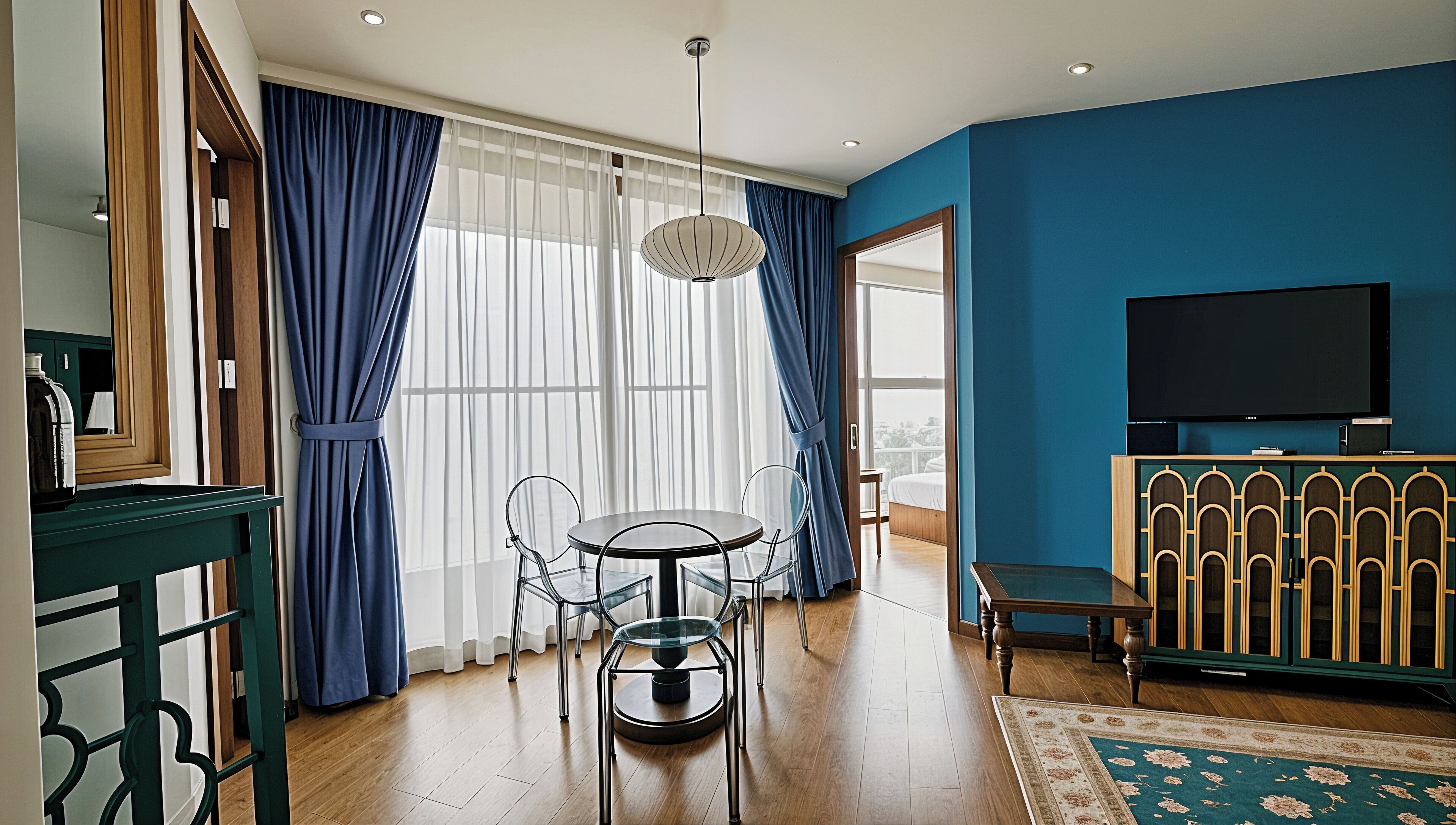 A modern hotel room with a dining area, a TV, and a view of the city.