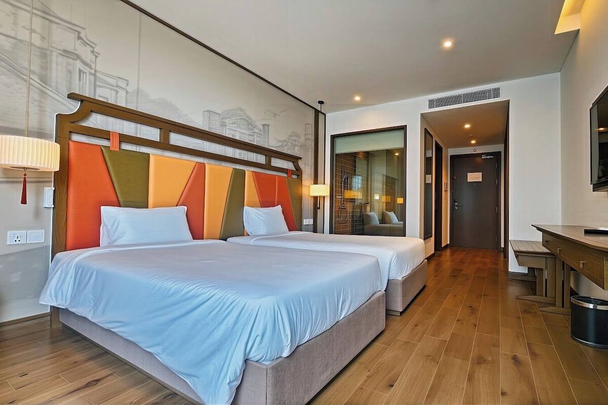 Une chambre d’hôtel avec un grand lit, un bureau et un miroir.